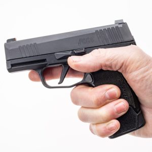 MTX 365 380 shown in pistol facing left with human hand gripping pistol. All parts are in black. Hand has a full ideal grip on pistol.