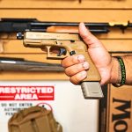 FDE Mag extension for 17 round magazine for Glock in tan pistol in hand facing left