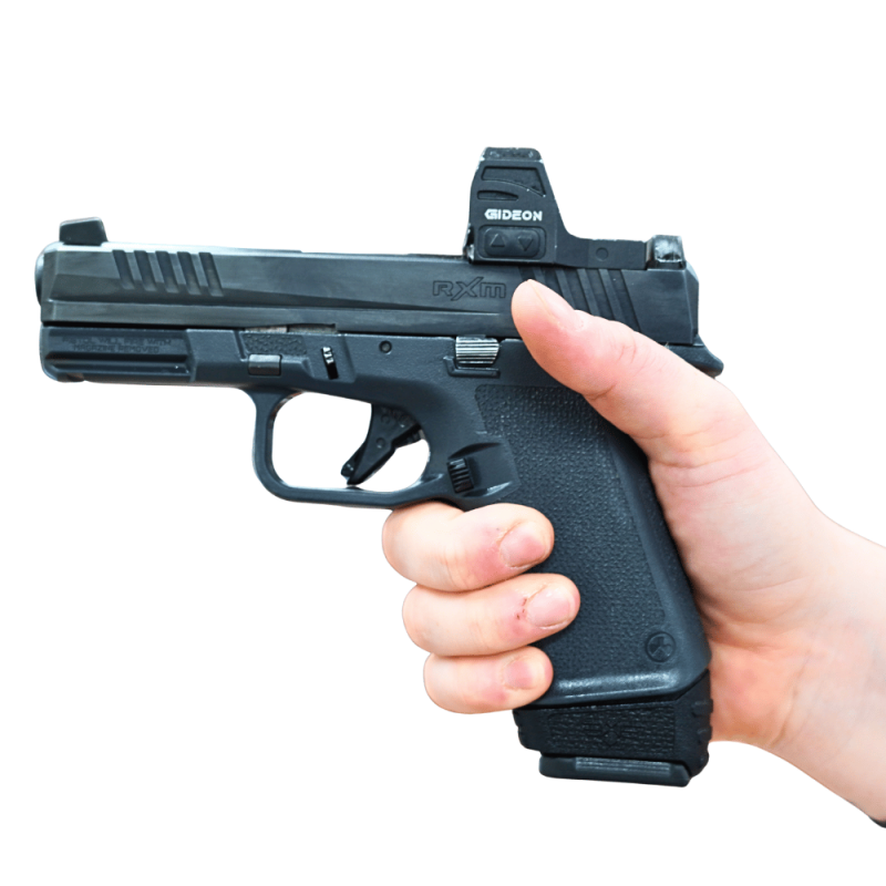 Extended mag for RXM with grip spacer shown in hand in pistol facing left