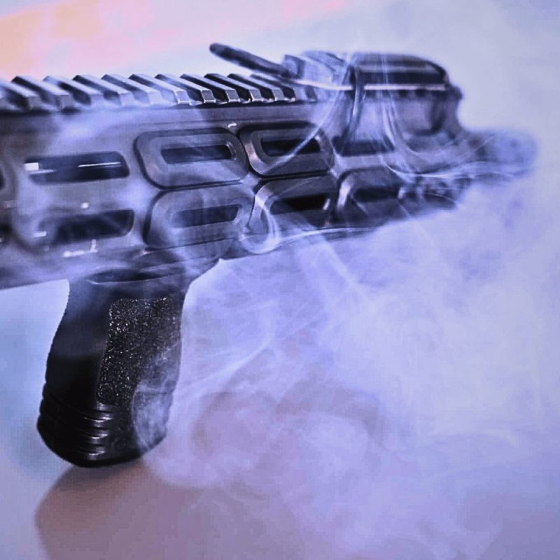 Smoke shown coming through the slots of a hand guard with rail covers in place in black.