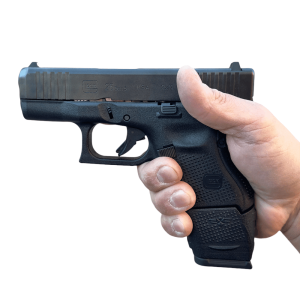 Extended Glock 26 clip in pistol in hand facing left